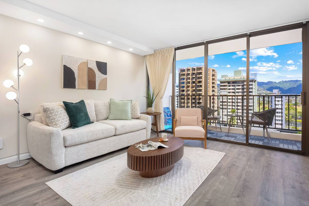 Ein modernes Wohnzimmer mit Sofa, Couchtisch und Balkon mit Blick auf die Stadt.