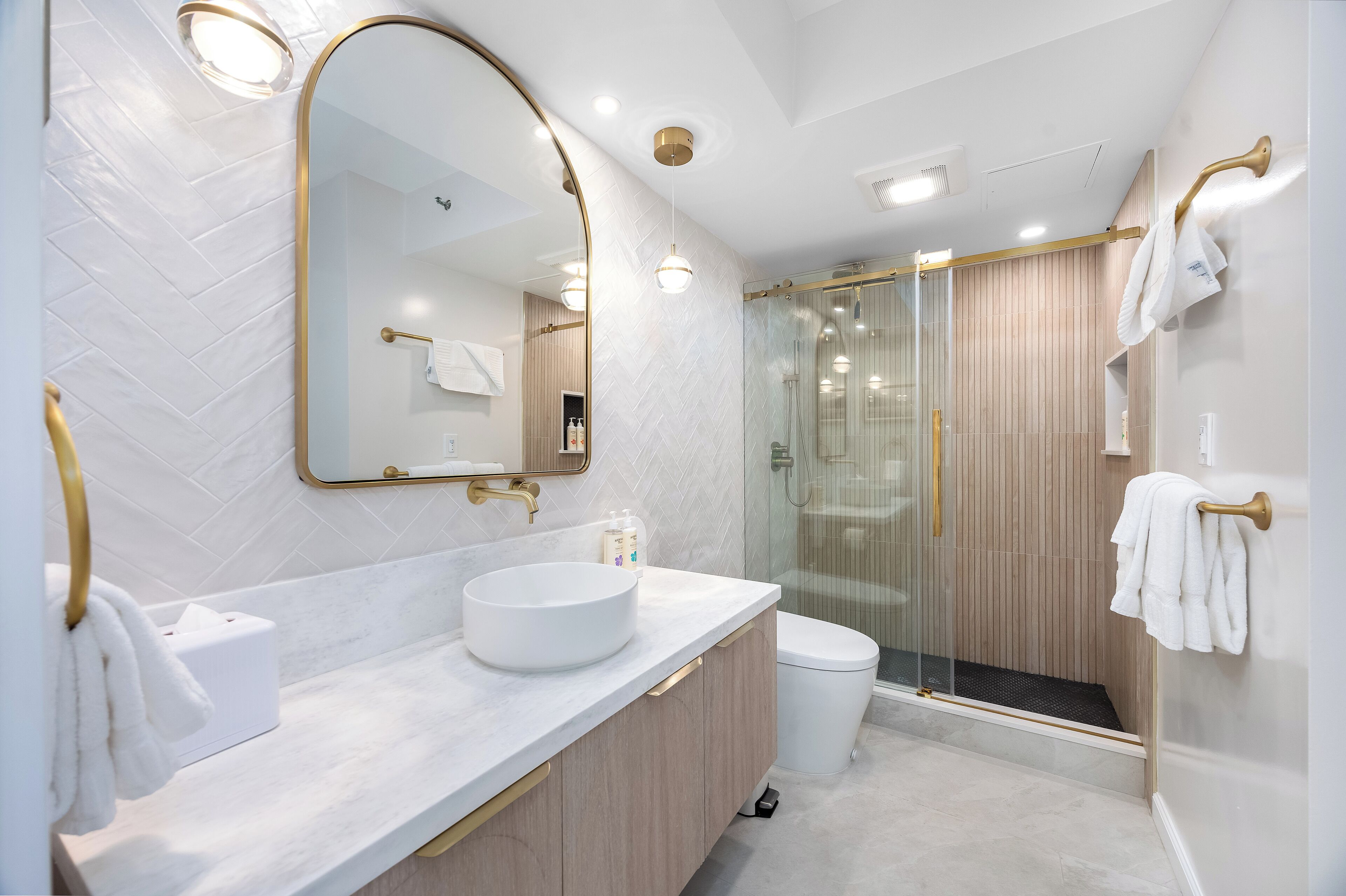 A modern bathroom with a large mirror, white sink, and a glass-enclosed shower area.