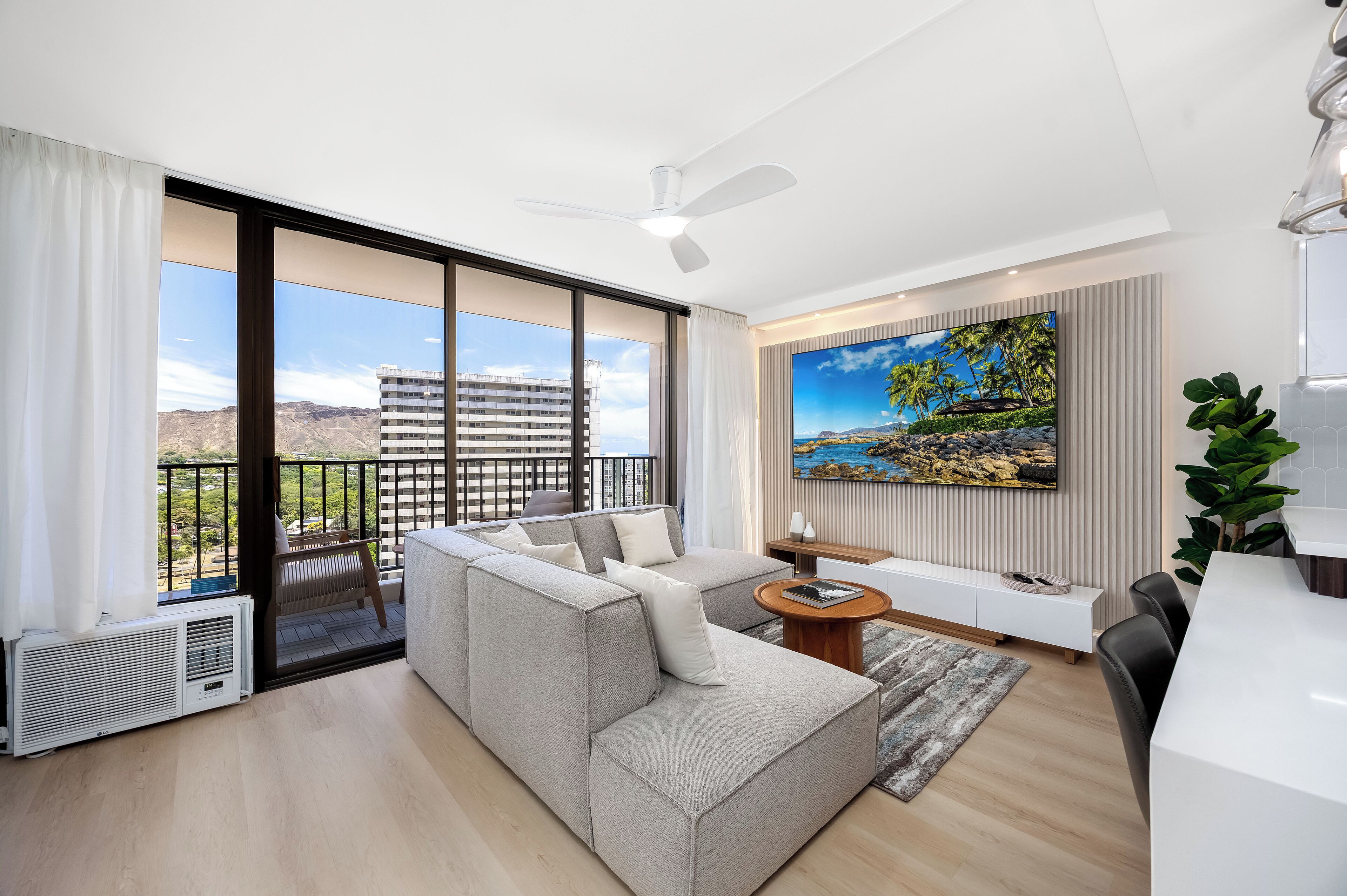 Ein modernes Wohnzimmer mit einer großen Eckcouch, einem Essbereich und einem Balkon mit Blick auf die Stadt.
