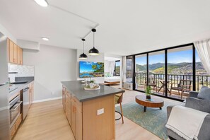 Eine moderne Wohnung mit Küche, Essbereich und einem Balkon mit Blick auf die Stadt.