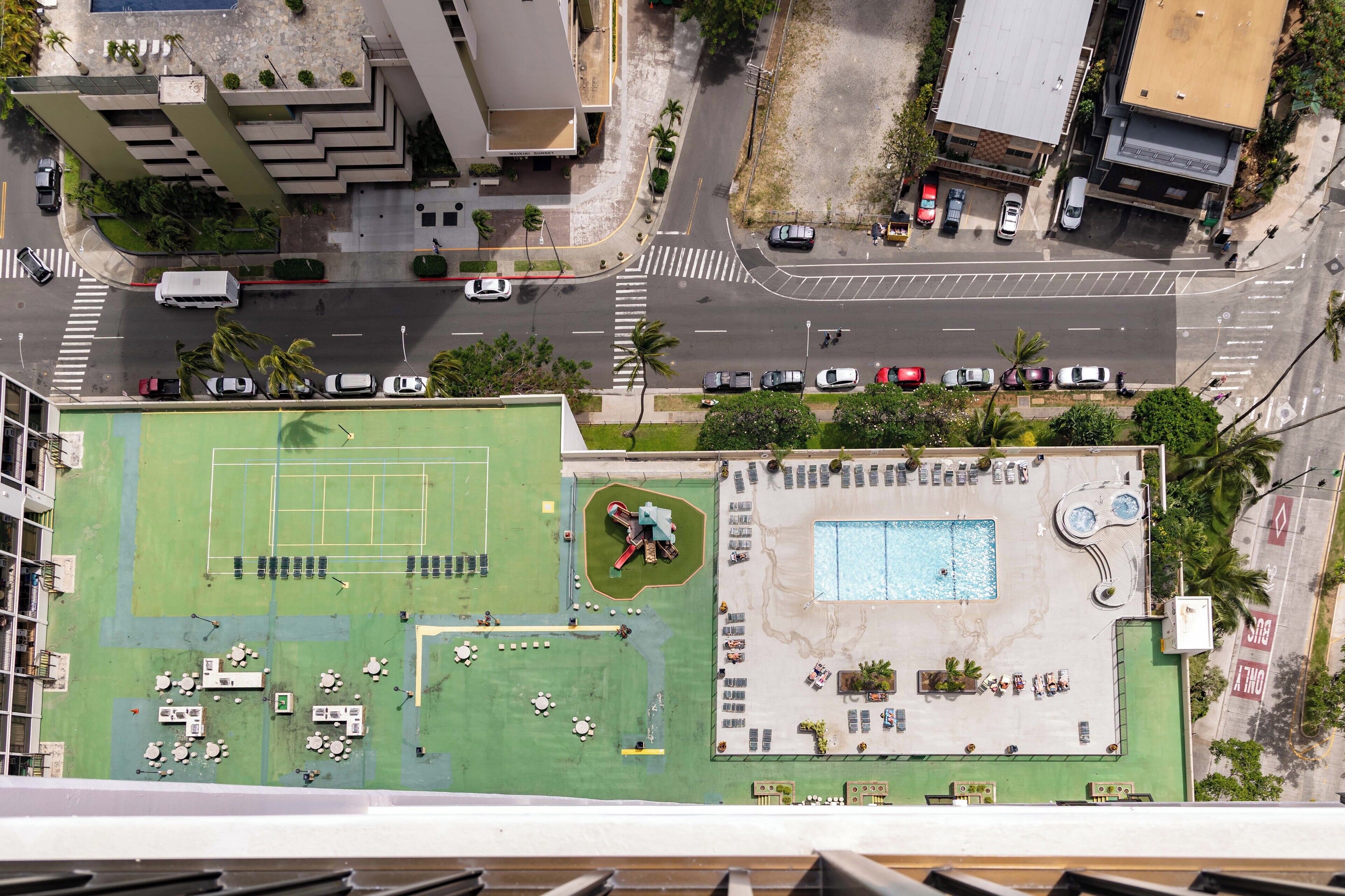 Vista aérea de um hotel com piscina no terraço, quadra de tênis e área de estar externa.