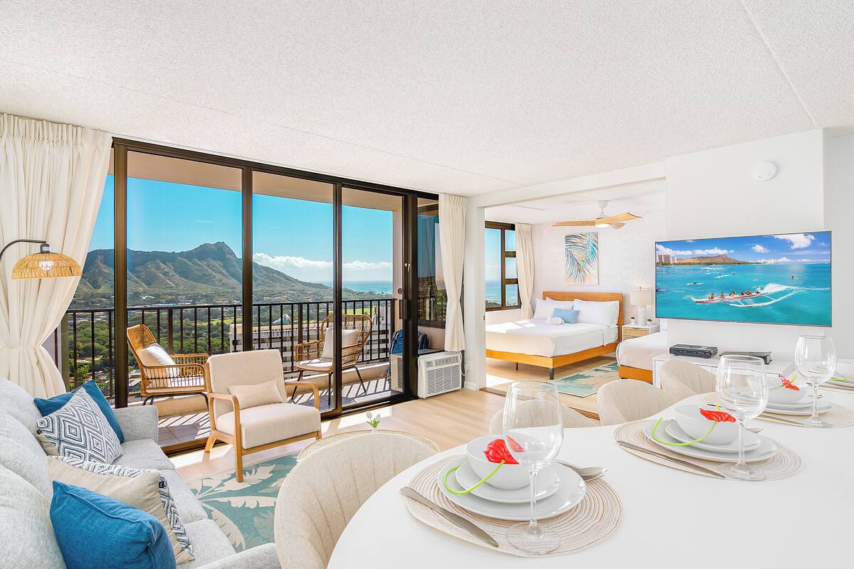 Une chambre spacieuse avec balcon, un lit, un coin repas et une grande fenêtre donnant sur la montagne.