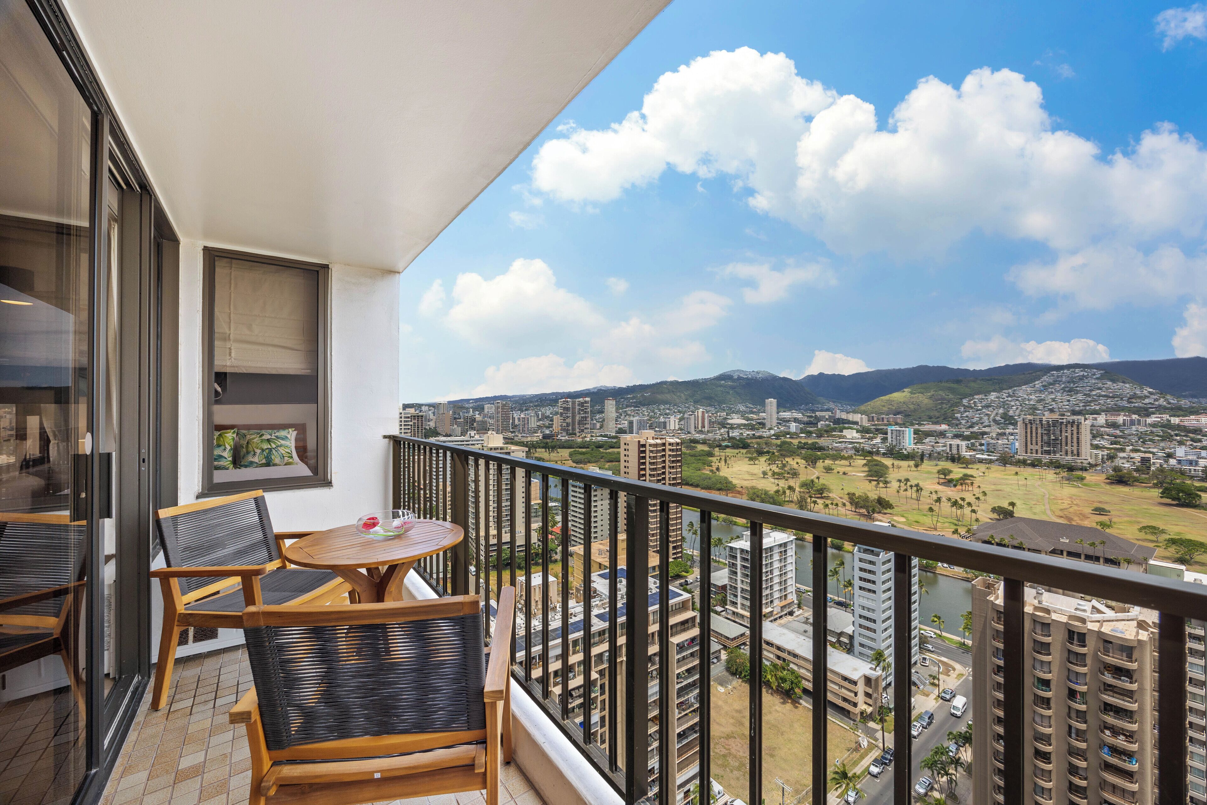 A balcony with a view of a cityscape, including tall buildings and a park.