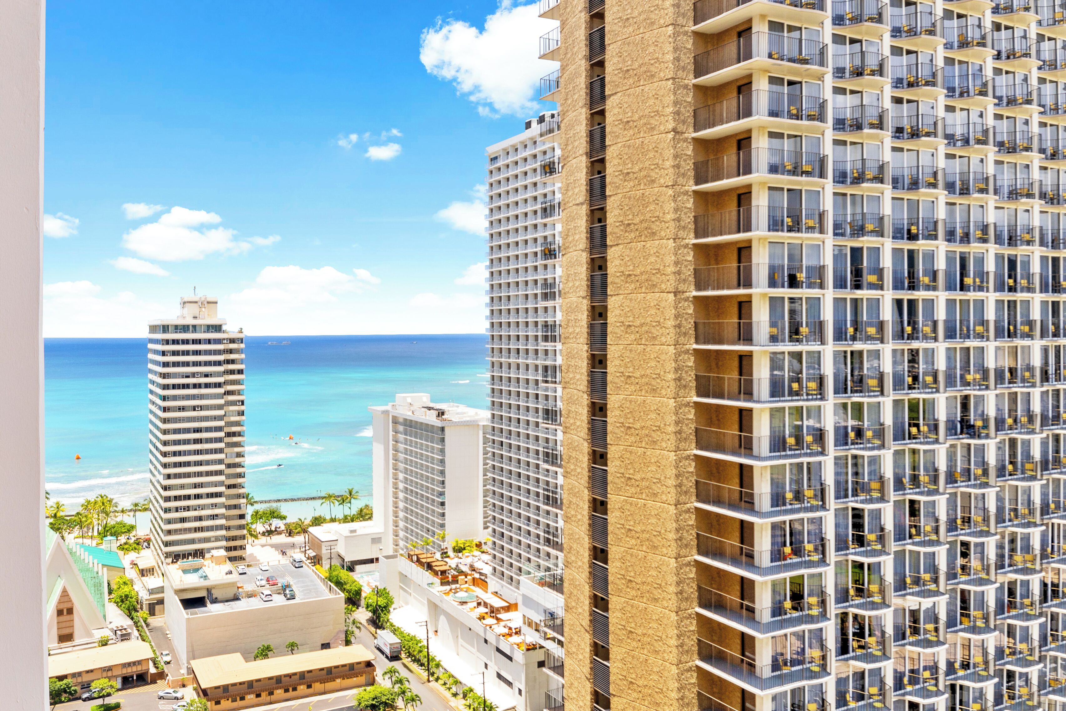 A high-rise hotel with multiple balconies, a view of the ocean, and a modern architectural design.