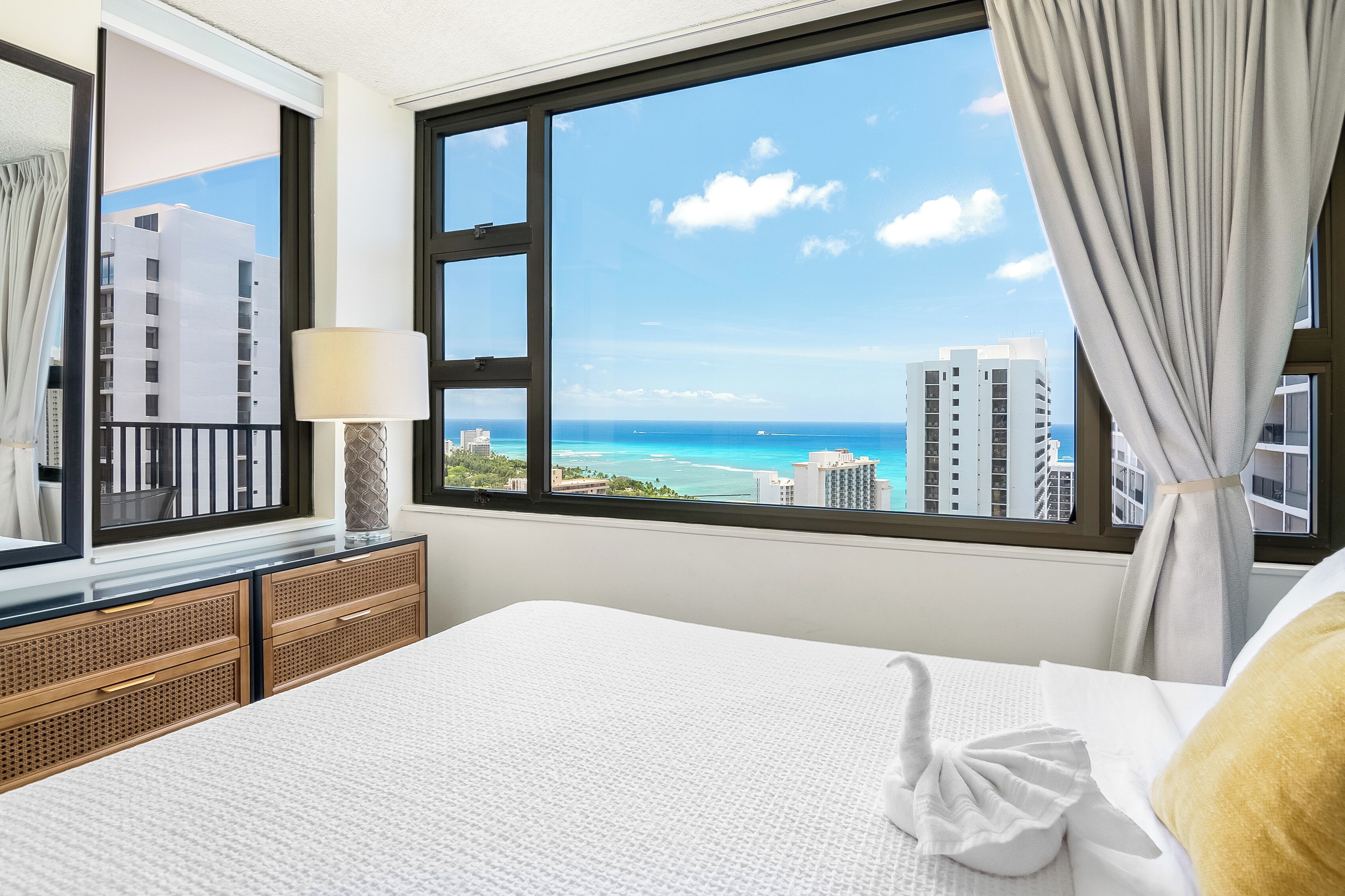 Ein Hotelzimmer mit großem Fenster und Blick auf das Meer und die Stadt.