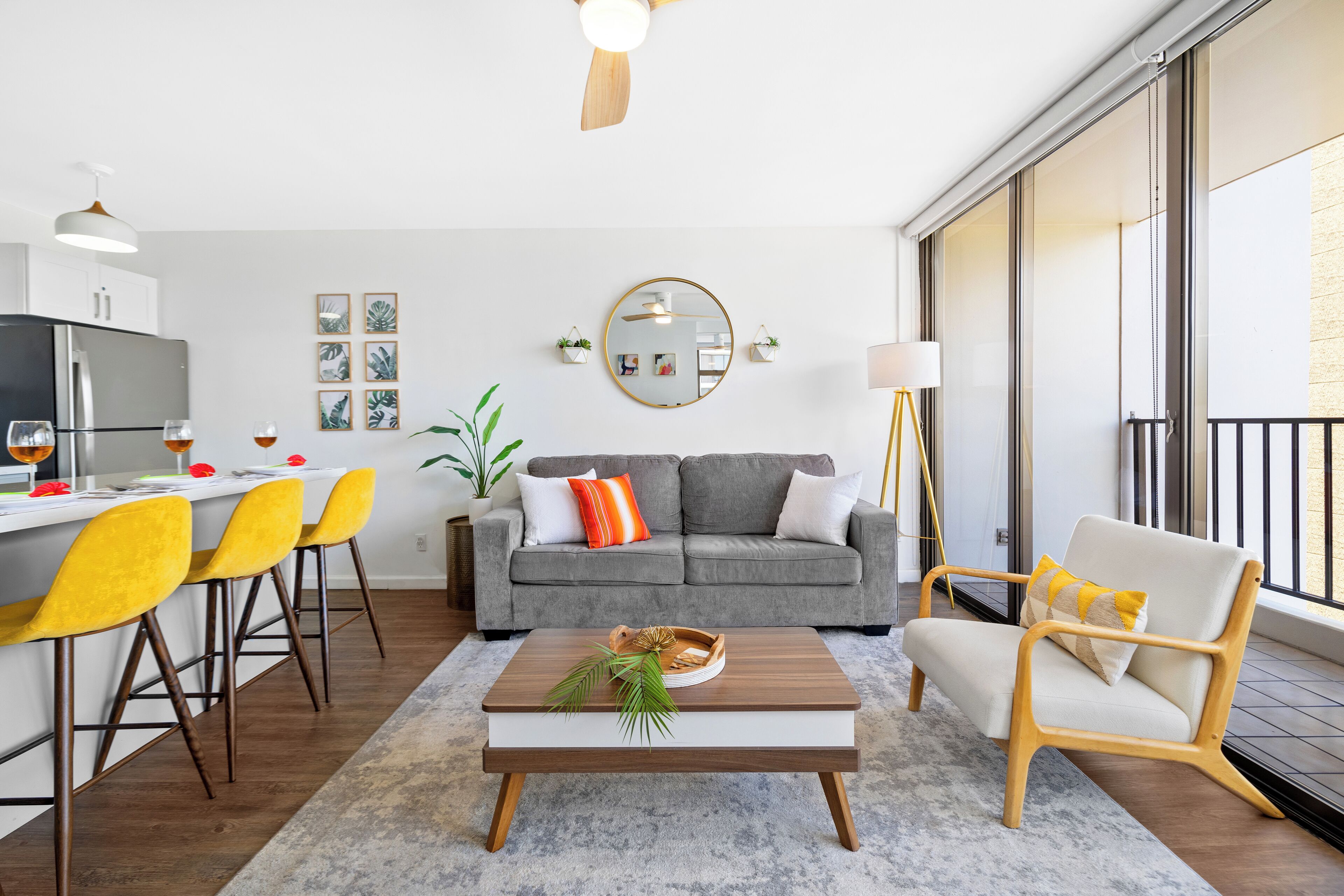 A modern living room with a grey sofa, yellow chairs, a wooden coffee table, and a large window.