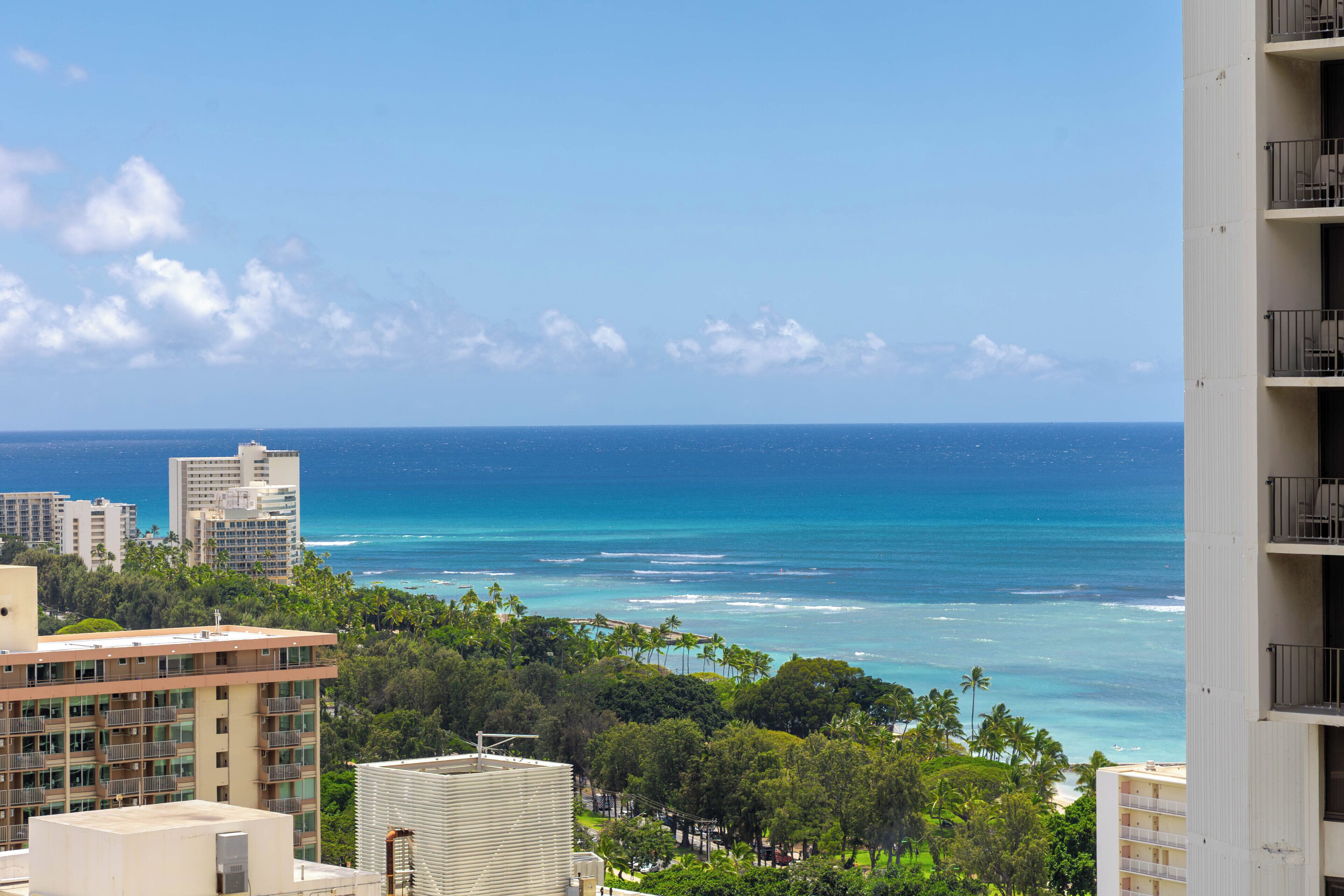 A coastal cityscape with high-rise buildings, a clear blue sky, and a view of the ocean.