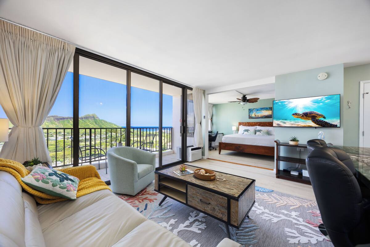 Quarto de hotel moderno com varanda, cama, escrivaninha e televisão.