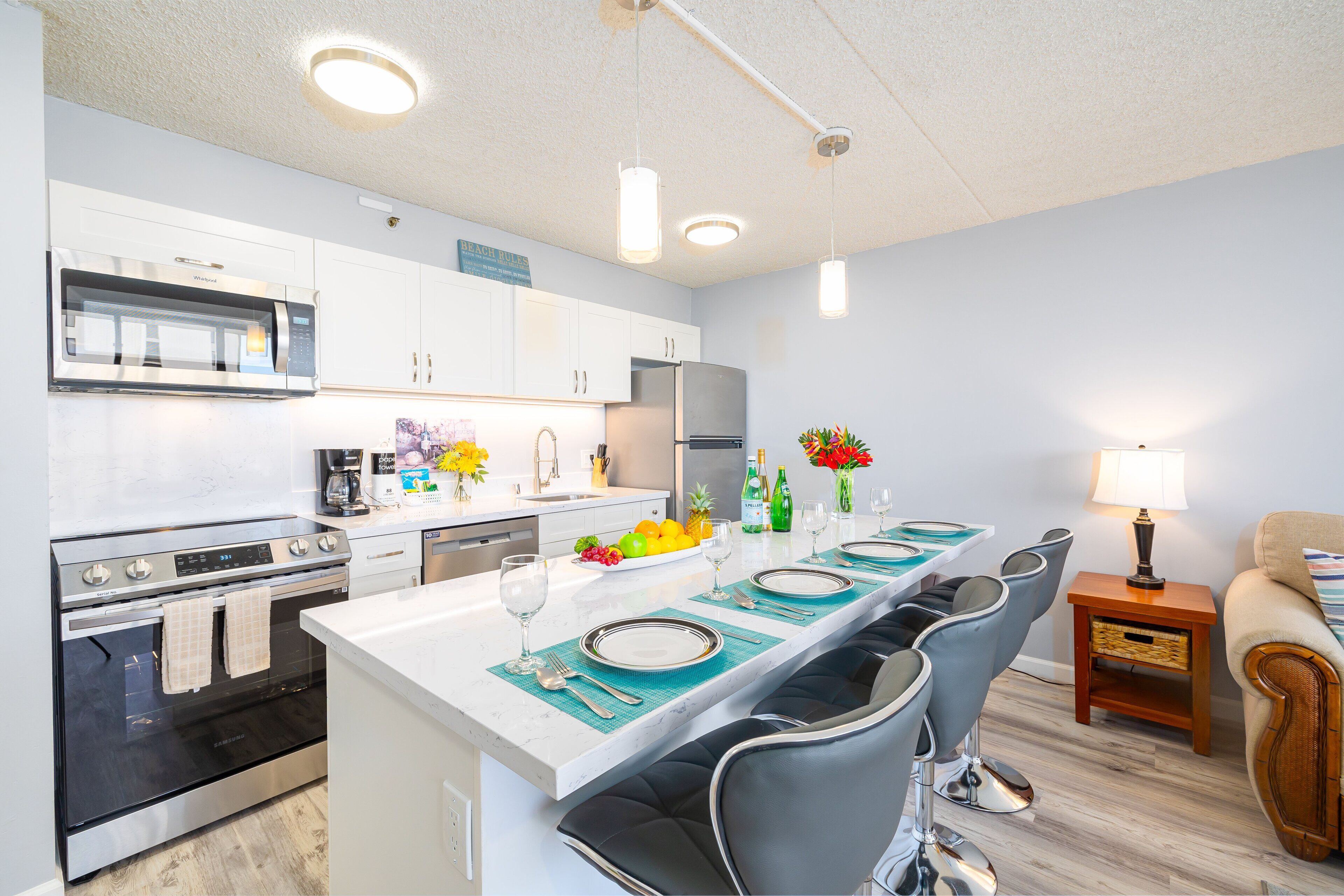 A modern kitchen with white cabinets, stainless steel appliances, and a central island with bar stools.