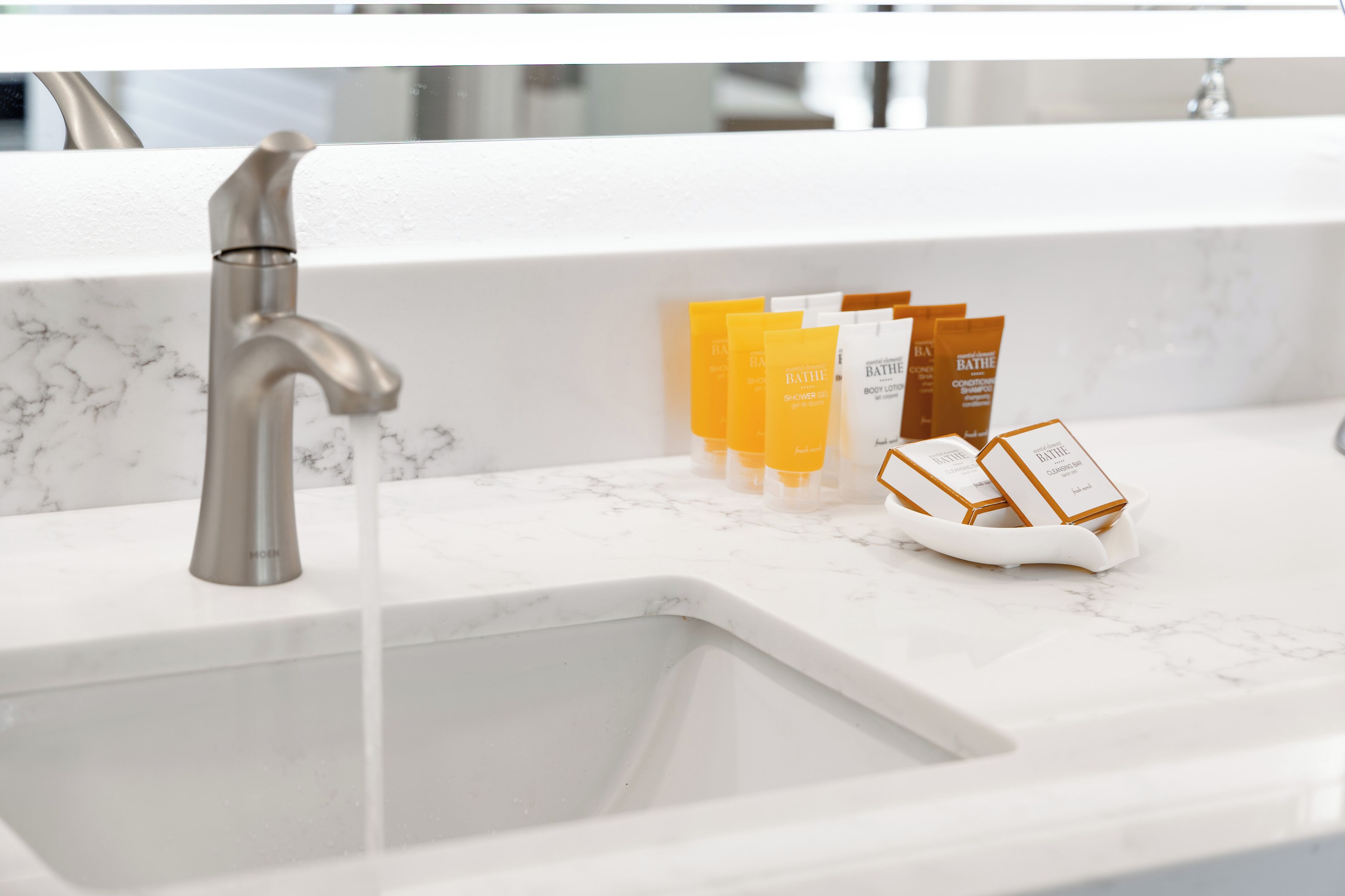 Un lavabo de salle de bain doté d’un robinet moderne et de produits de toilette, notamment une lotion pour le corps et un gel douche.