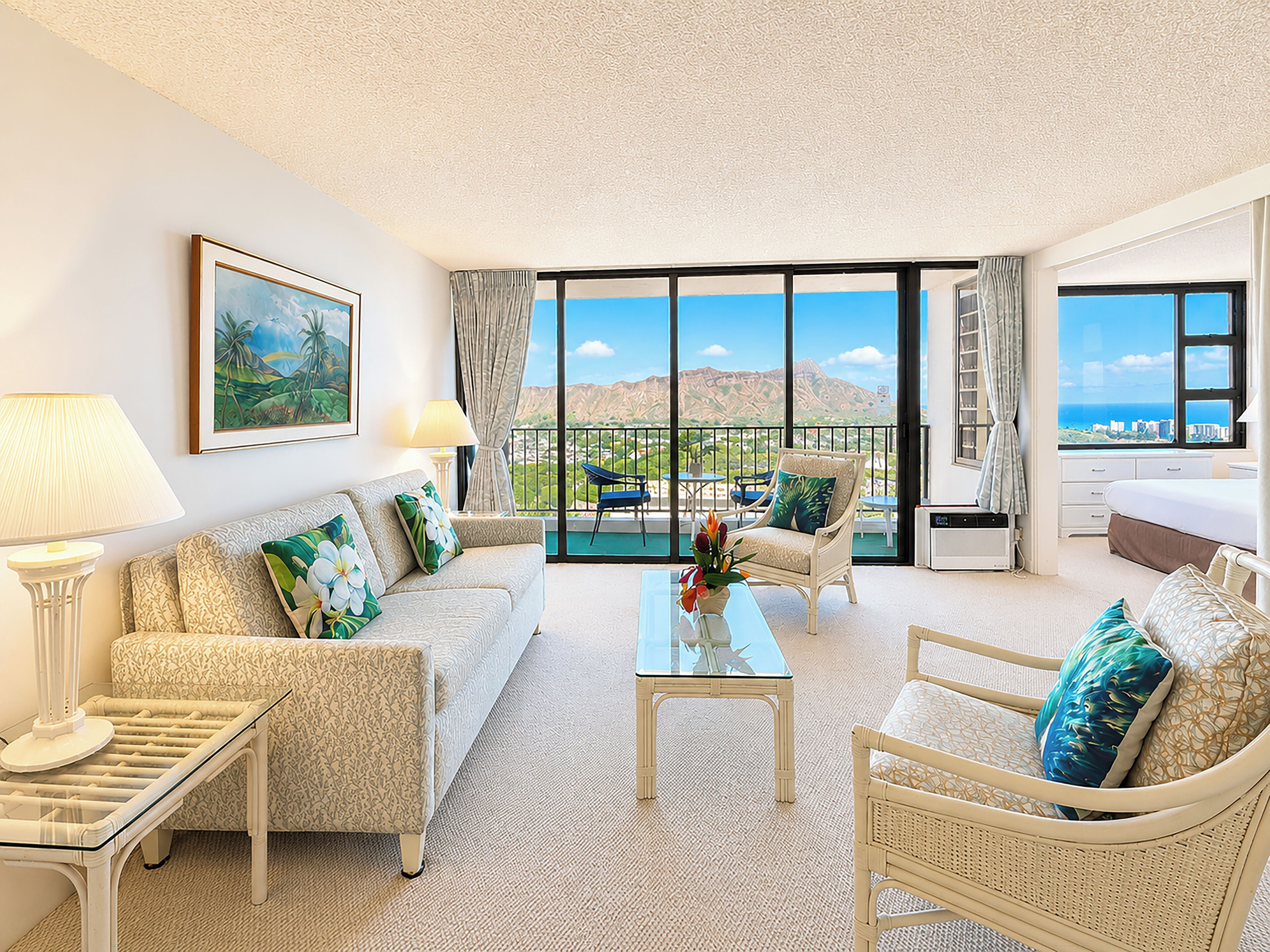 Ein geräumiges Wohnzimmer mit Sofa, Sesseln, Couchtisch und einem Balkon mit Blick.