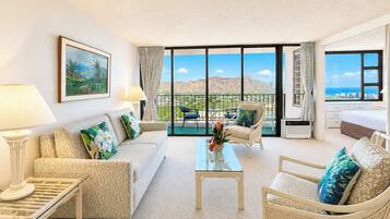 Ein geräumiges Wohnzimmer mit Sofa, Sesseln, Couchtisch und einem Balkon mit Blick.