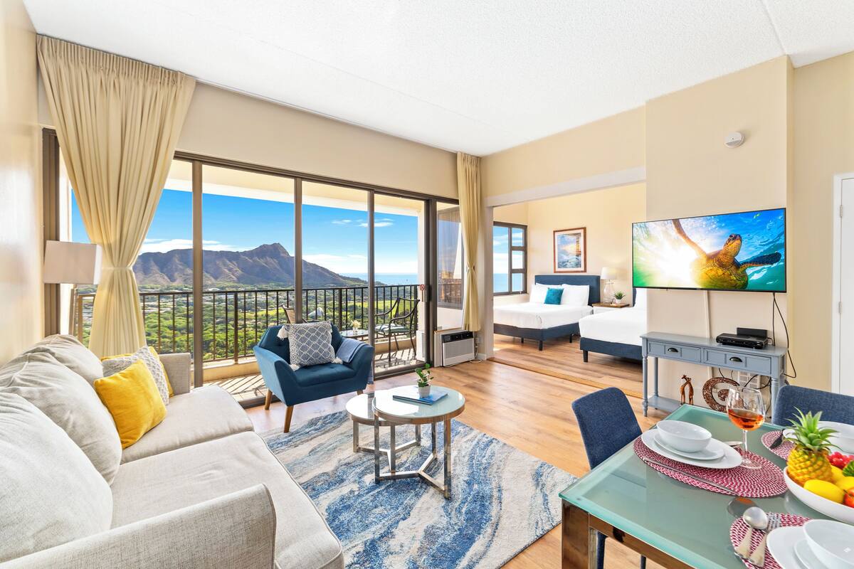 Une chambre d’hôtel moderne dotée d’un balcon, d’un canapé, d’une table à manger et d’un téléviseur.