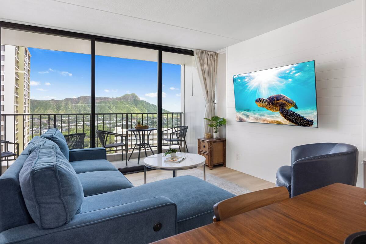 Un salon moderne avec balcon, un grand téléviseur et une vue sur les montagnes.