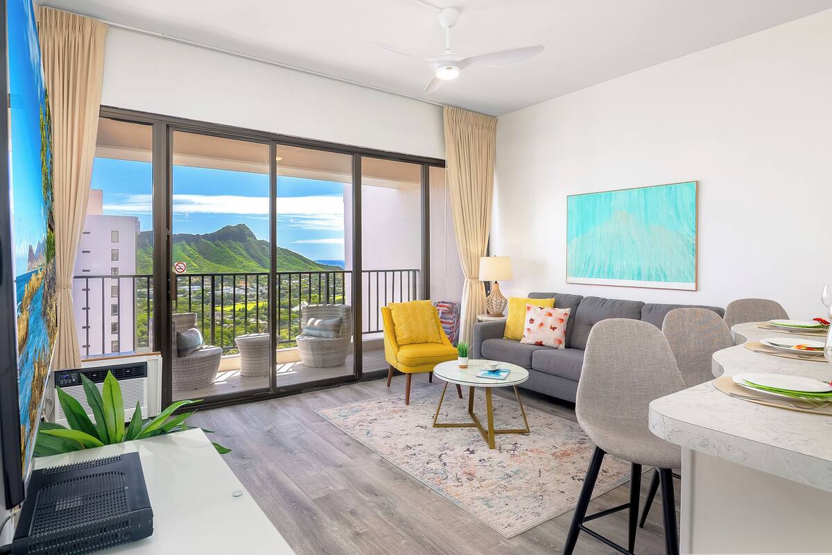 Un salon moderne avec un balcon, un canapé, une table à manger et une grande fenêtre donnant sur les montagnes.