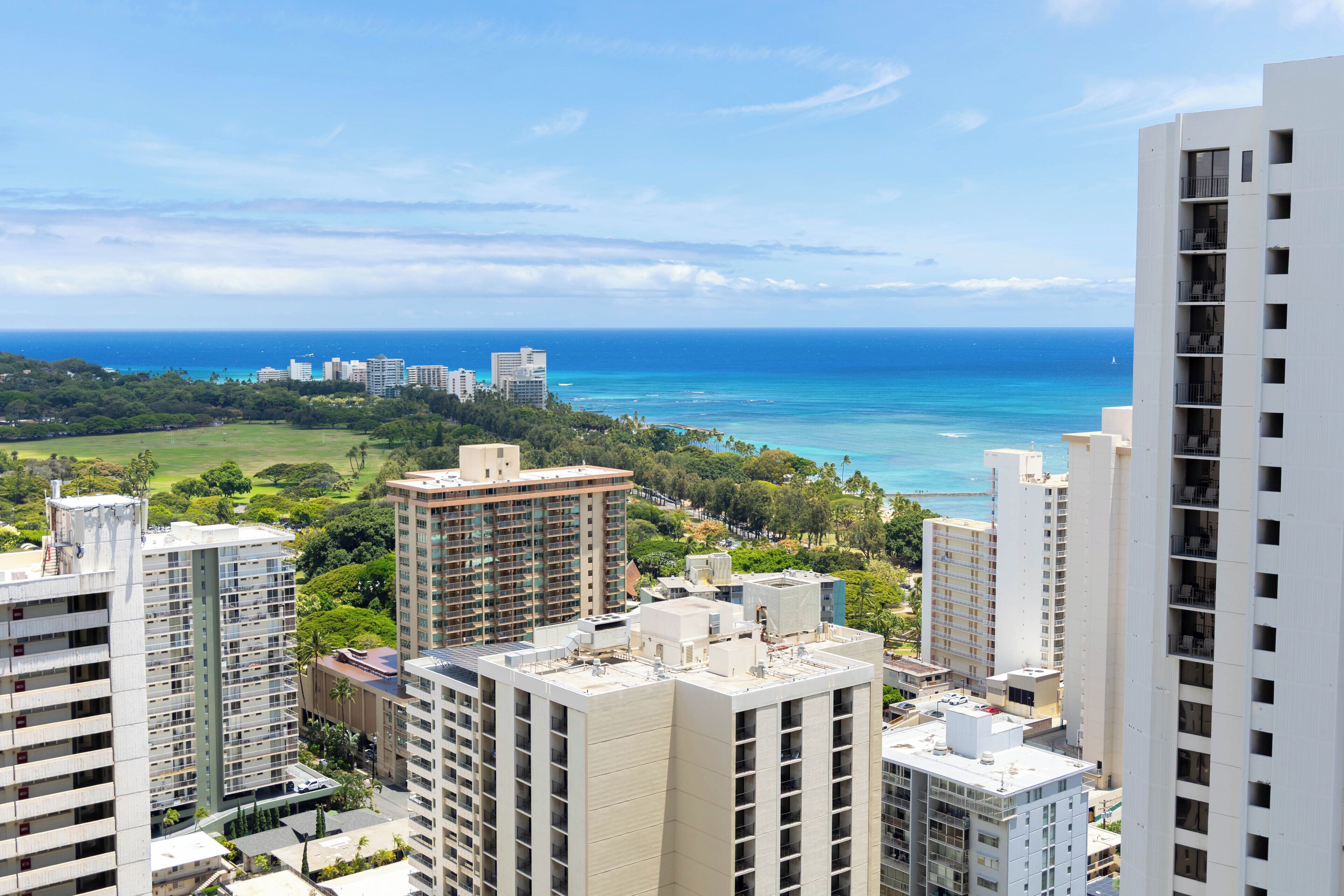 A high-rise building with multiple floors, surrounded by other buildings and a view of the ocean.