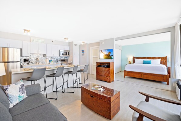 A modern hotel room with a kitchen area, a dining space, and a large bed. - High Floor Ocean View Condo (King Bed and Parking) (Honolulu)