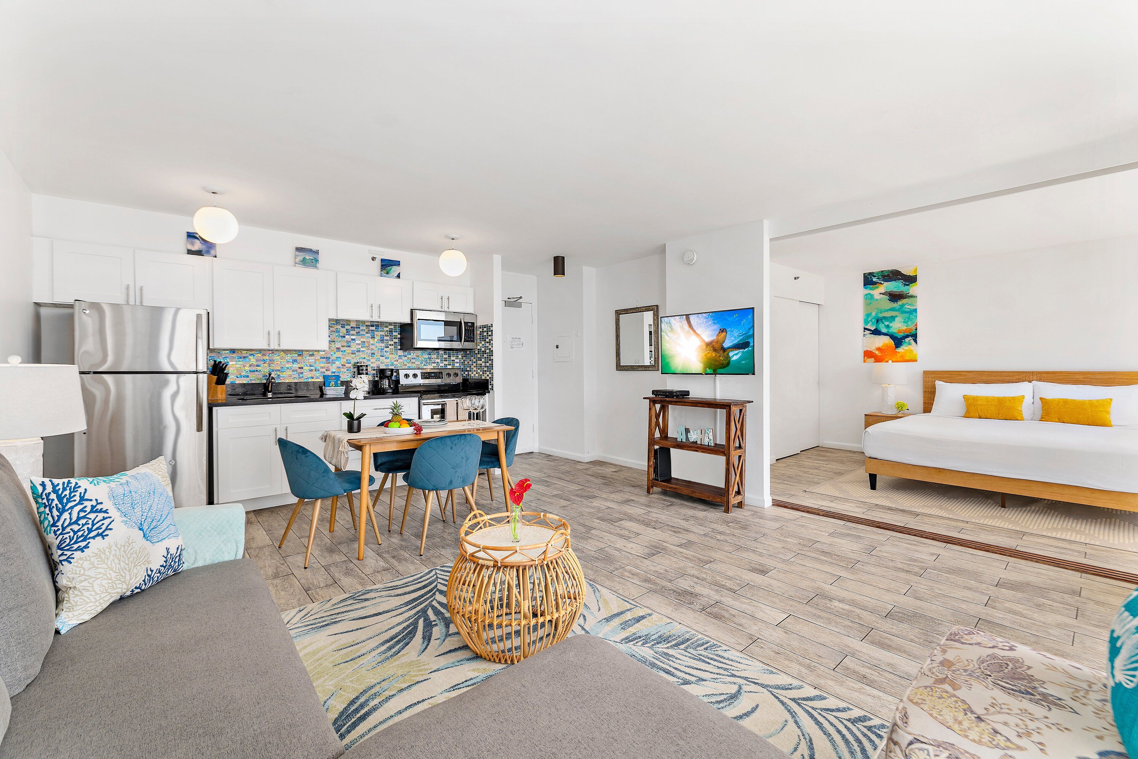 Un espace de vie moderne et compact comprenant un coin cuisine, un coin repas et une chambre.