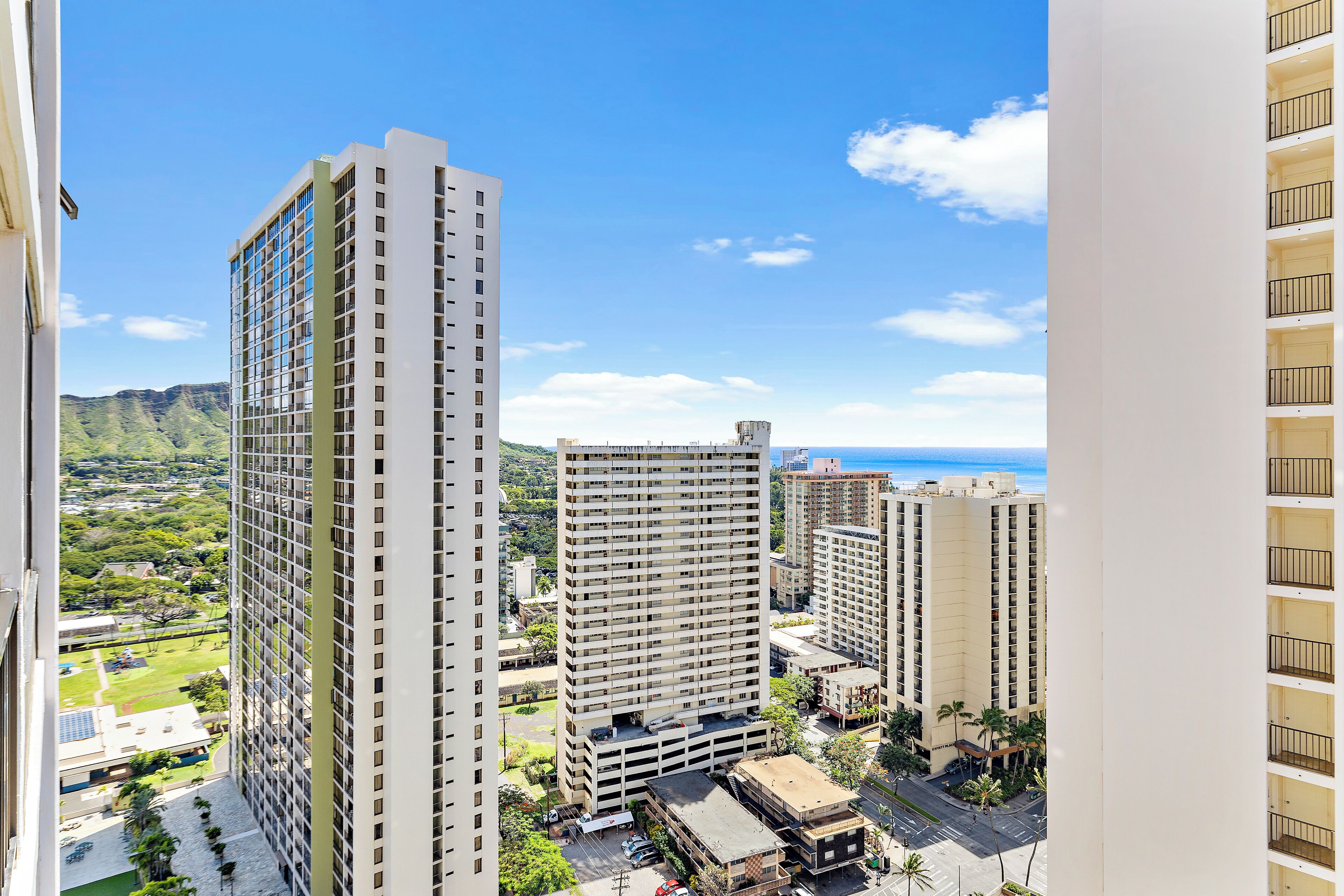 A high-rise building with multiple floors, a parking area, and a view of the ocean.