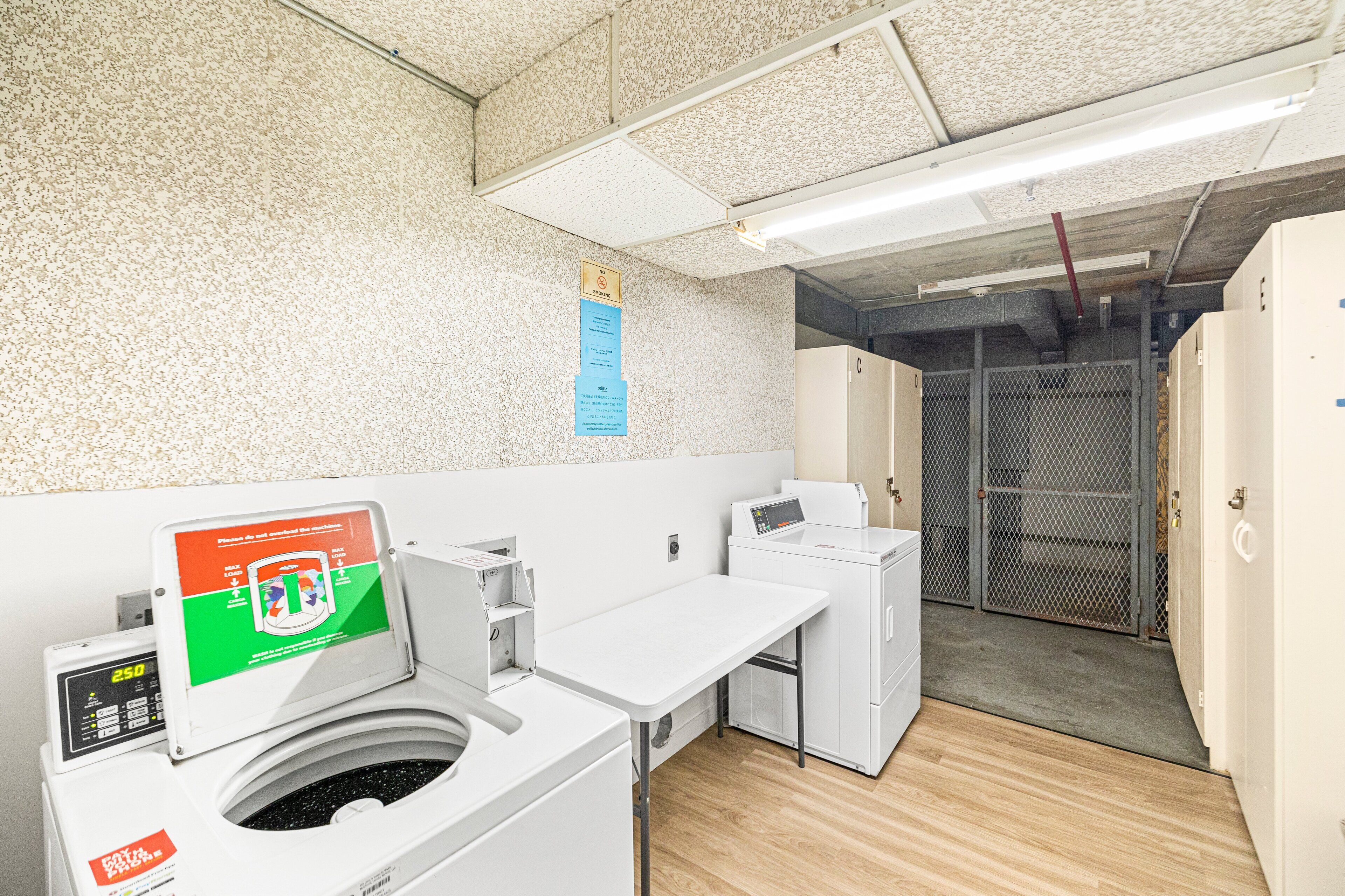 A laundry facility with industrial washing machines, a control panel, and a metal gate leading to a storage area.