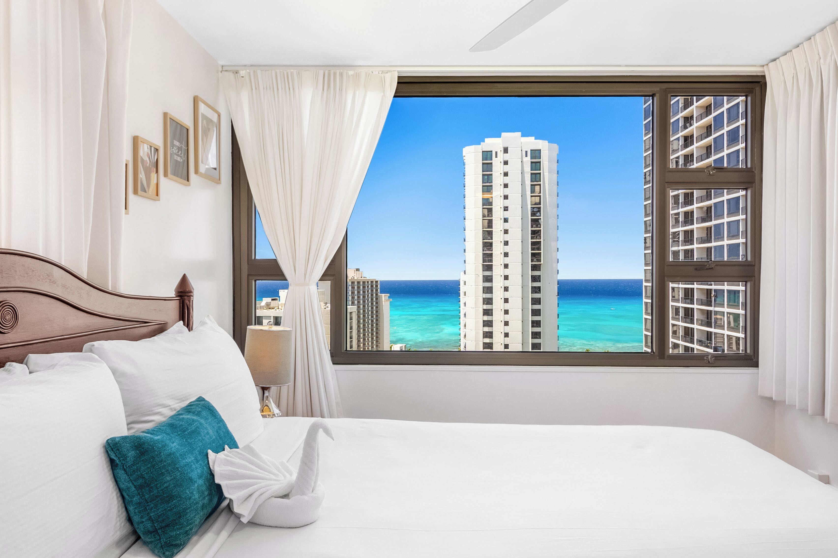 A hotel room with a large window offering a view of a tall building and the ocean.