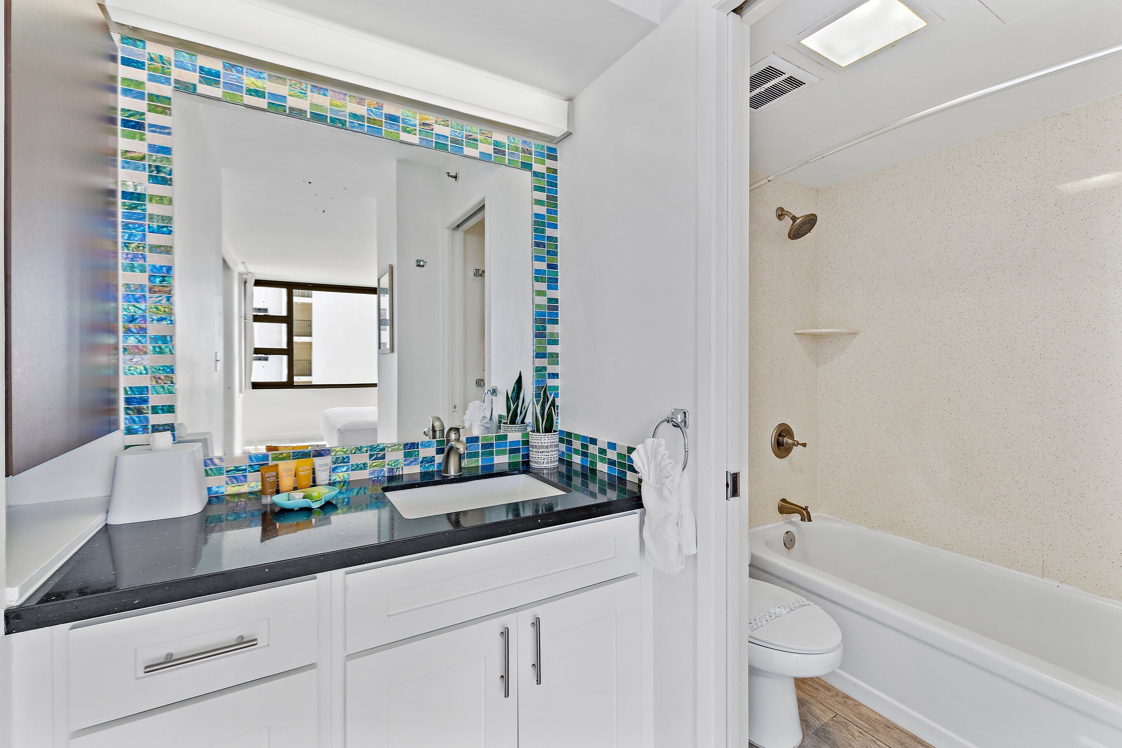A bathroom with a white sink, a mirror, a toilet, and a bathtub.
