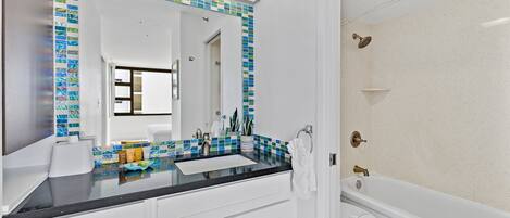 A bathroom with a white sink, a mirror, a toilet, and a bathtub.