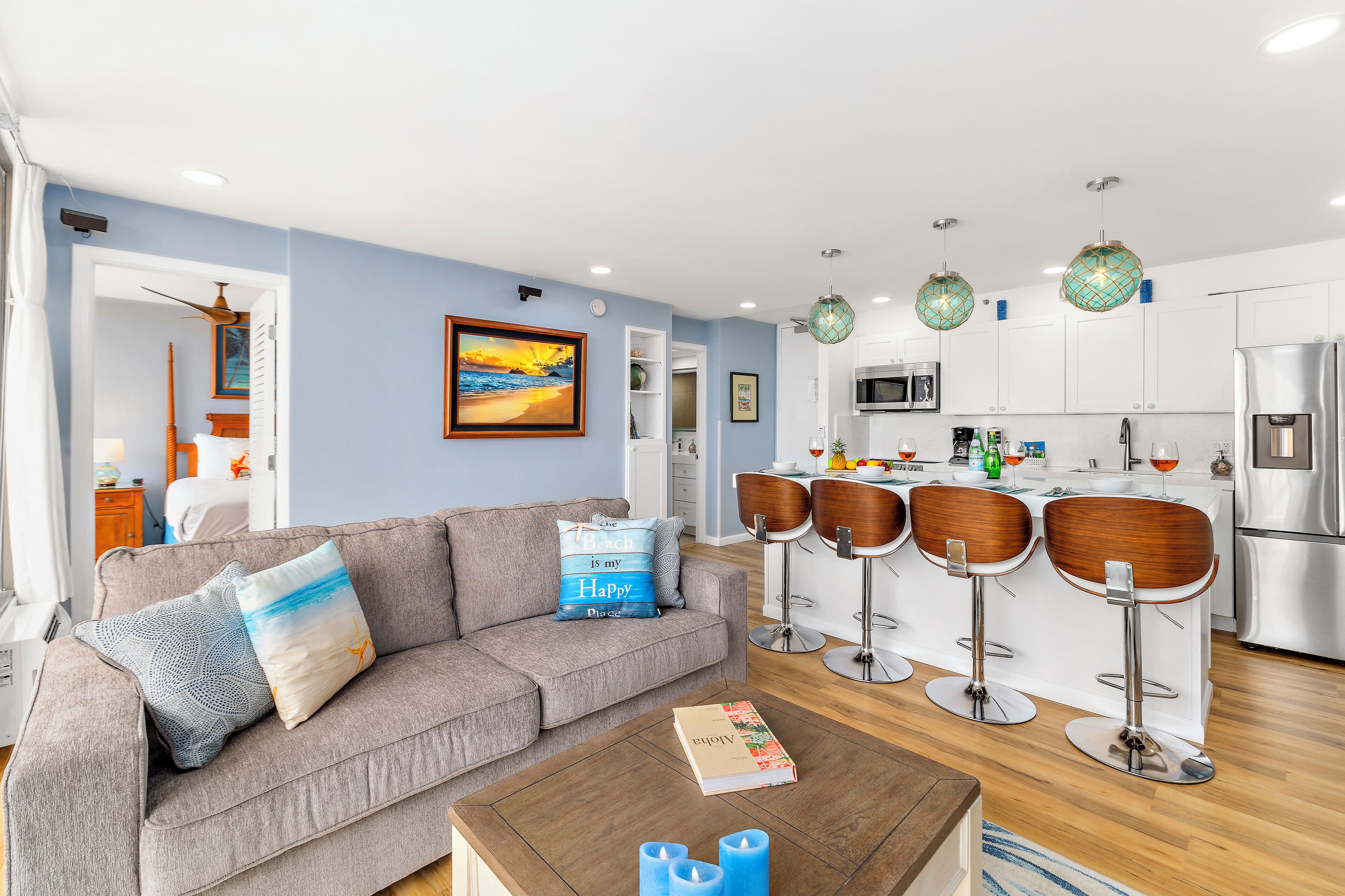 A modern living room with a sofa, a coffee table, and a kitchen area with bar stools.