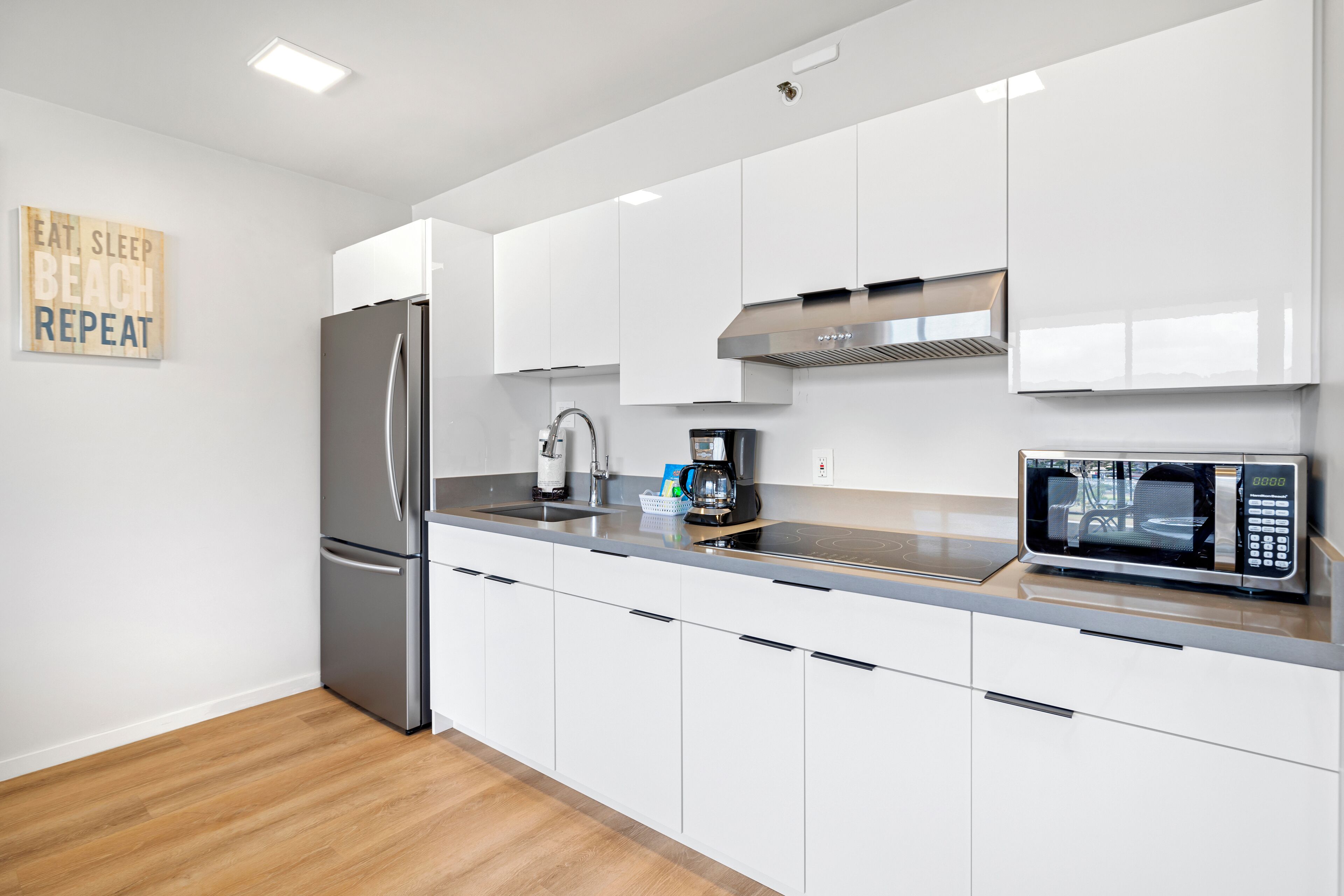 Een moderne keuken met witte kastjes, roestvrijstalen apparatuur en een houten vloer.