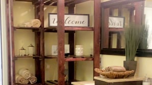 Een houten rek met 'Welcome'-borden, een gootsteen en een witte vloerkleed in een hoek.