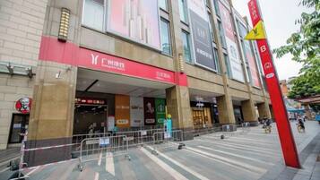 A commercial building with multiple storefronts, including a prominent red sign and a yellow directional sign.