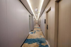 A hotel corridor with doors on both sides, a carpet with a cloud pattern, and a ceiling light fixture. - Yimi Hotel (Tianhe City branch of Guangzhou Beijing Road subway station) (Guangzhou)