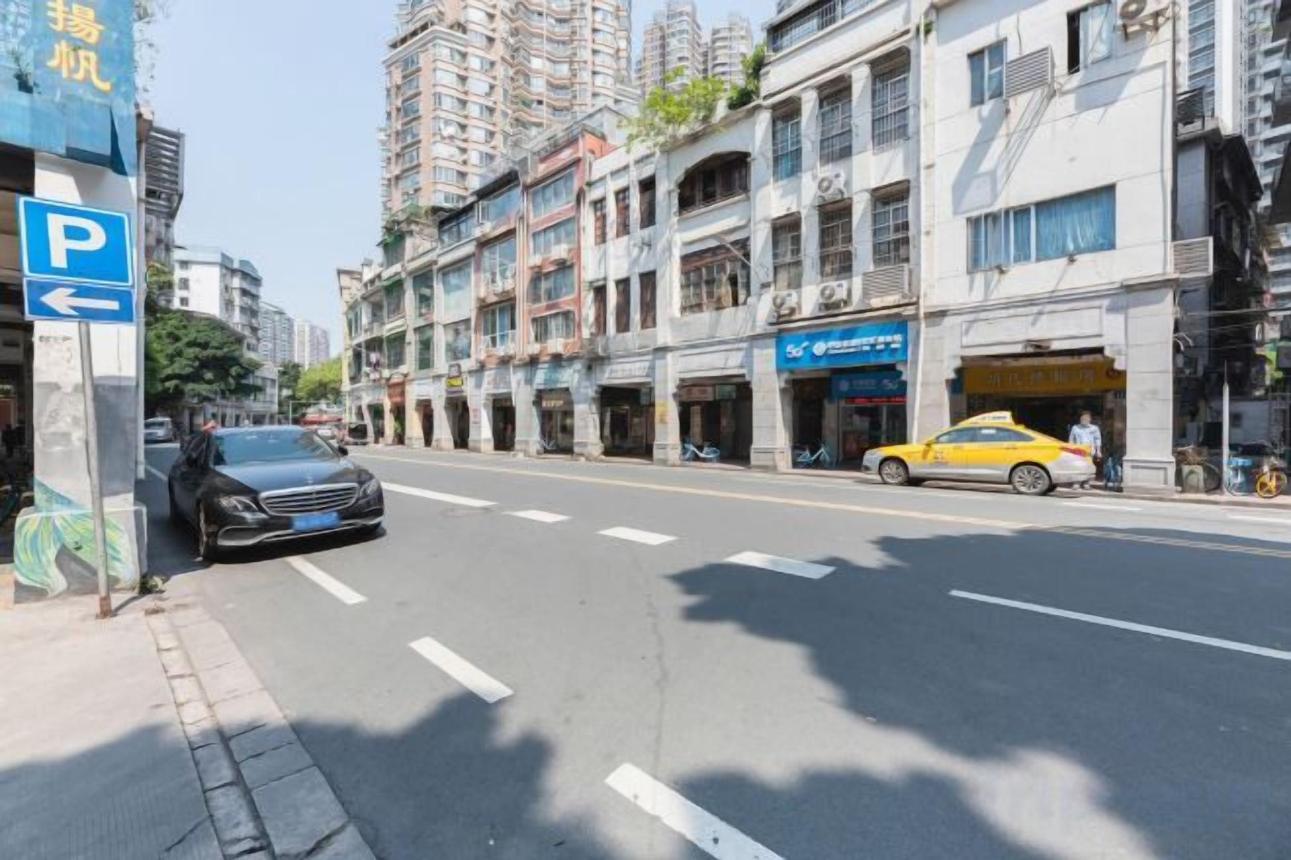 Une rue avec un panneau de stationnement bleu, une voiture noire et un taxi jaune.