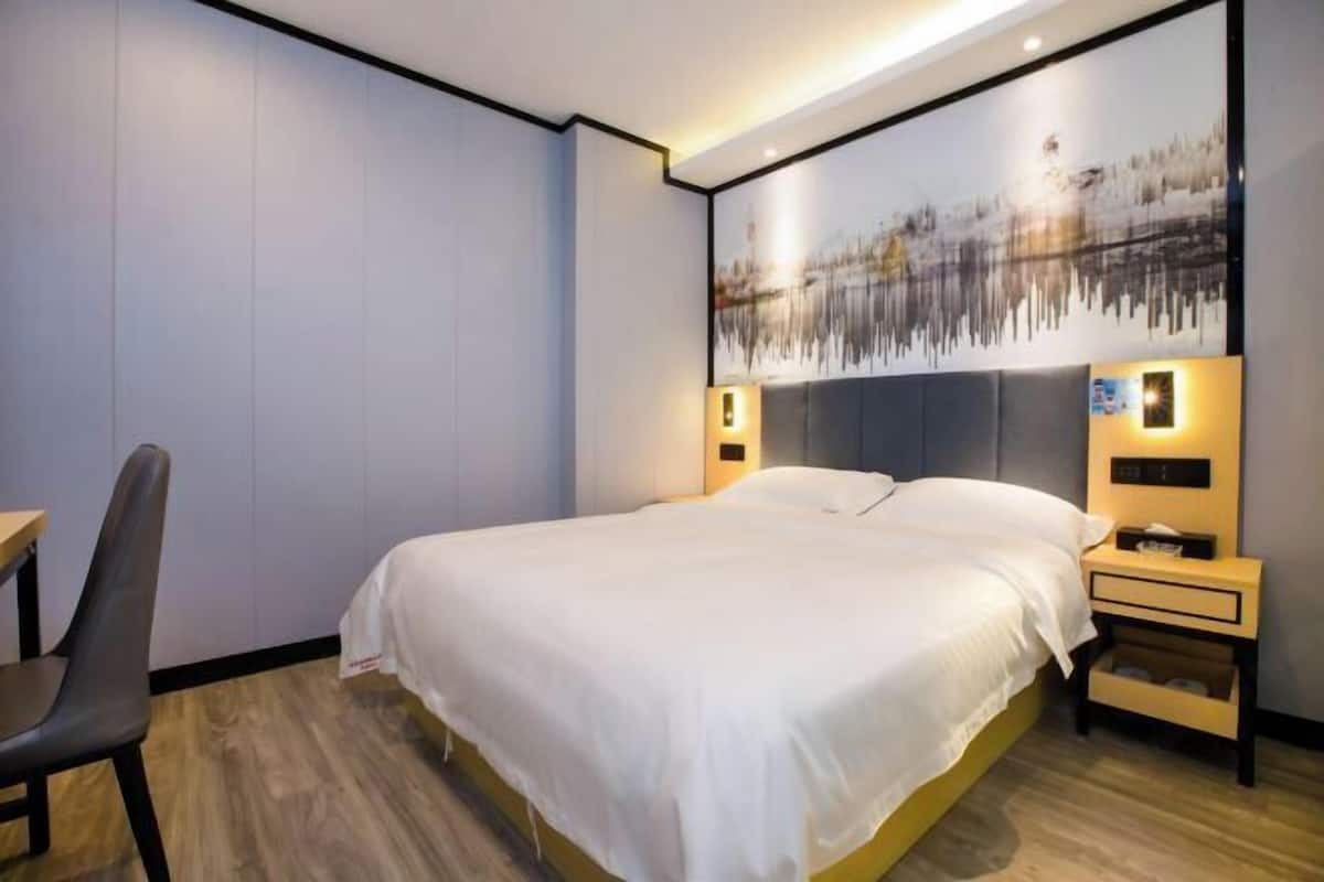 A modern hotel room with a large bed, a desk, and a chair.