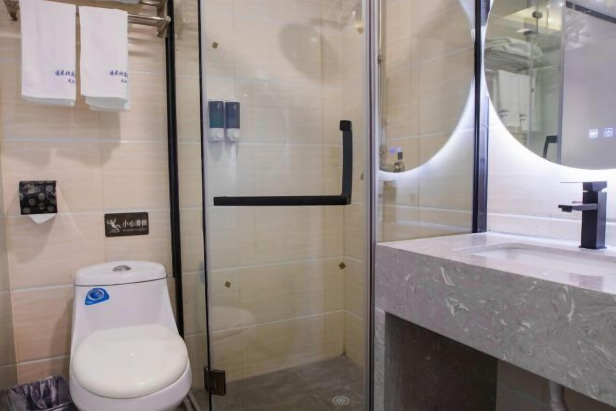 A modern bathroom with a glass-enclosed shower, a white toilet, and a marble sink.