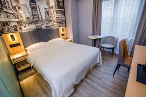 A hotel room with a bed, bedside tables, a chair, a small table, and a cityscape mural on the wall. - Yimi Hotel (Tianhe City branch of Guangzhou Beijing Road subway station) (Guangzhou)