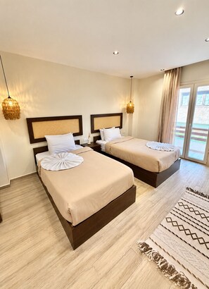 A hotel room with two beds, a large window, and a patterned rug. - solima pyramids inn (Giza)