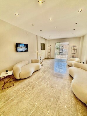A spacious living area with a large window, a flat-screen TV mounted on the wall, and a seating arrangement with two sofas and a coffee table. - solima pyramids inn (Giza)