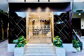A reception area with a glass door, a staircase leading up, and potted plants on either side. - solima pyramids inn (Giza)