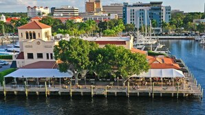 Un restaurante frente al agua con terraza, un muelle y un puerto deportivo con barcos.