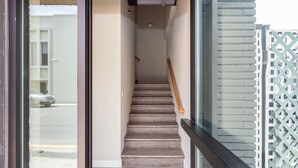A staircase leading to an upper floor, with a wooden handrail and a glass door at the bottom.