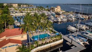 Ein Yachthafen mit zahlreichen vertäuten Booten, einem Schwimmbad und einem Gebäude mit der Aufschrift "Yacht Brokerage".