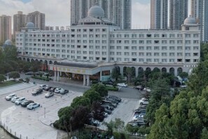 Un grand hôtel à plusieurs étages, doté d’un parking et d’une entrée principale surmontée d’un auvent.