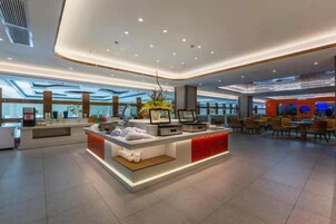 Un moderno vestíbulo de hotel con una recepción central, zona de estar y grandes ventanales.