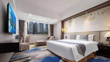 Ein Hotelzimmer mit einem großen Bett, einem Schreibtisch, einem Stuhl und Blick auf die Stadtlandschaft.