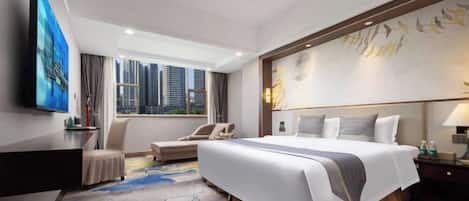 A hotel room with a large bed, a desk, a chair, and a view of the city skyline.