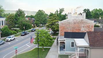 A street view with a brick building, a small porch, and a flag on the sidewalk.