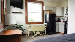 A compact kitchen with a wooden table and chairs, a black refrigerator, and white cabinets.