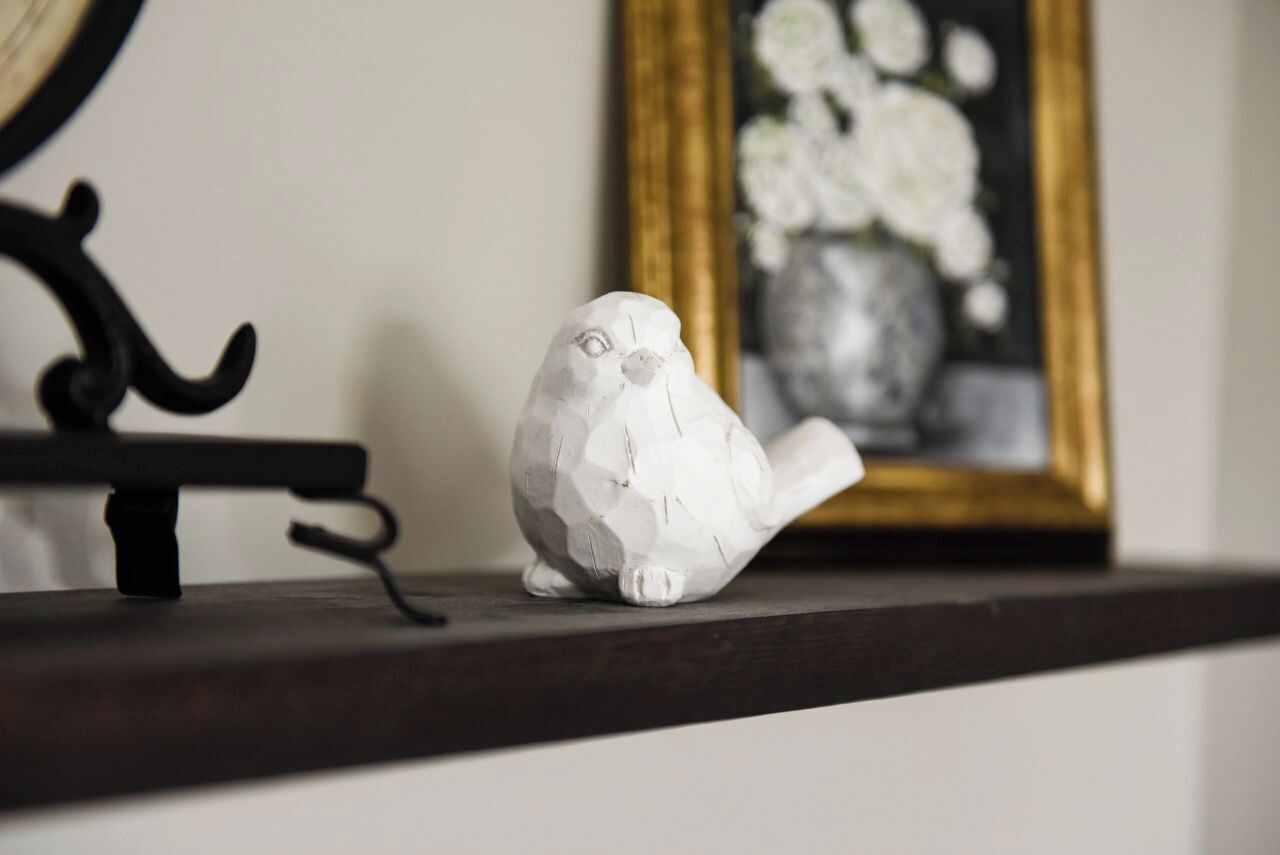 A white ceramic owl figurine on a dark wooden shelf.