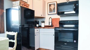 A compact kitchen with a refrigerator, microwave, stove, and oven.